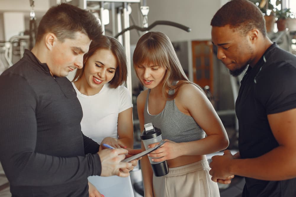 Entrenador personal en gimnasio con clientes