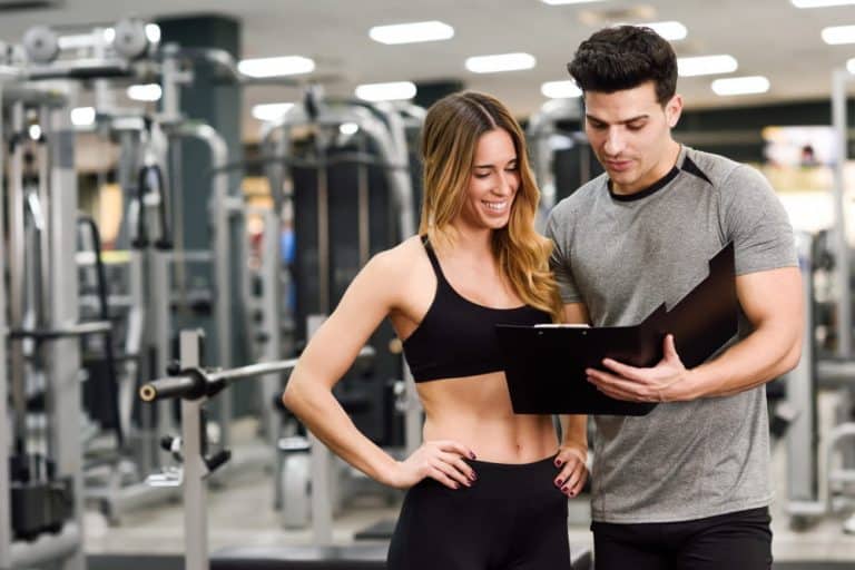 entrenador personal explicando plan en un cuaderno a mujer